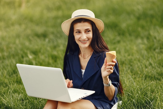 Vrouw in een lentestad. Dame met een laptop. Meisje zittend op een gras.