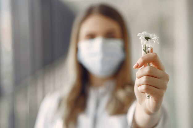 Vrouw in een masker en uniform met een bloem in haar handen