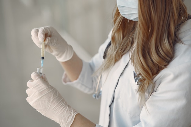 Vrouw in een masker en uniform met een spuit in haar handen