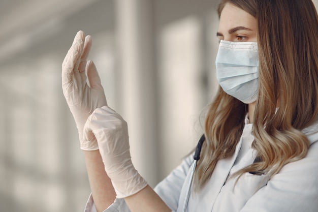 Vrouw in een masker en uniform zet op handschoenen