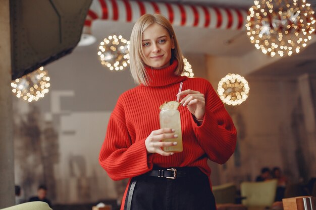 Vrouw in een rode trui. Dame drinkt een cocktail.