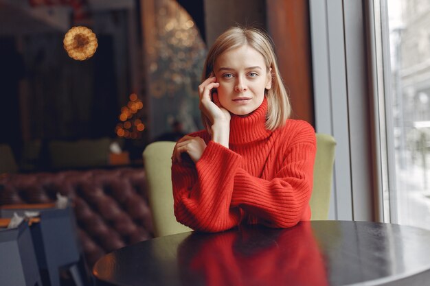 Vrouw in een rode trui. Dame in een restaurant.