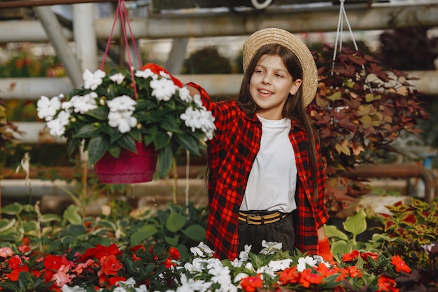 Vrouw in een rood overhemd. Werknemer met flowerpoots. Dochter met planten