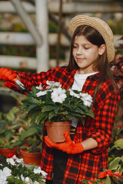 Vrouw in een rood overhemd. Werknemer met flowerpoots. Dochter met planten
