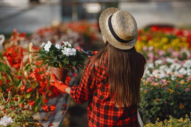 Vrouw in een rood overhemd. Werknemer met flowerpoots. Dochter met planten