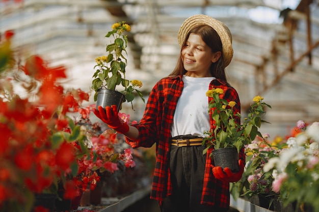 Vrouw in een rood overhemd. Werknemer met flowerpoots. Dochter met planten