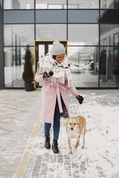 Vrouw in een roze jas, wandelende hond