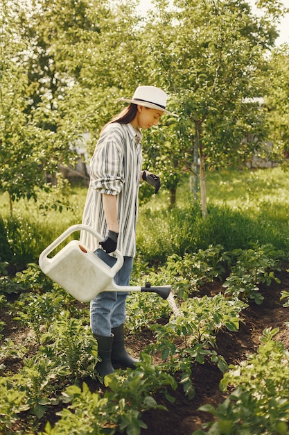 Vrouw in een trechter van de hoedenholding en werkt in een tuin