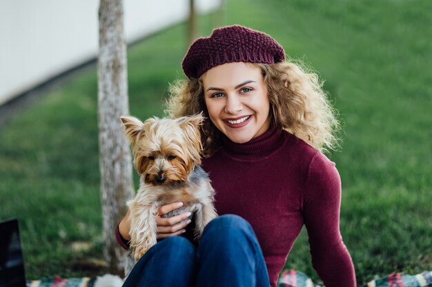 Vrouw in een violette hoed bij een picknick in het bos, met haar hond Yorkshire Terrier. zonlicht, felle kleurverzadiging, eenheid met de natuur.