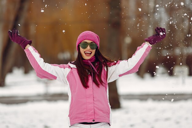 Vrouw in een winterpark. Dame in roze sportpak. Meisje in een zonnebril.