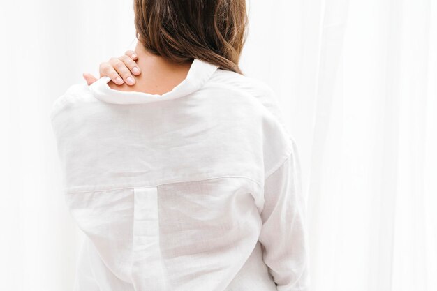 Vrouw in een wit linnen overhemd dat haar nek aanraakt