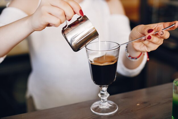 Vrouw in een witte sweater gietende melk in koffiedessert