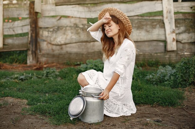 Vrouw in een zomer-veld. Meisje in een witte jurk. Vrouw met vat melk.