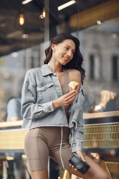 Vrouw in een zomerstad. Dame met ijs. Brunette bij het gebouw.