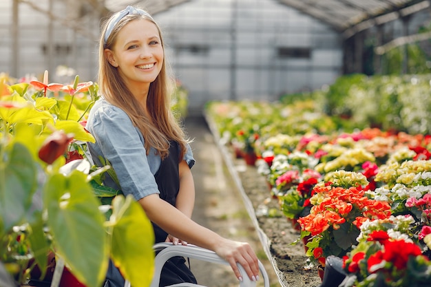 Vrouw in een zwarte schort die in een serre werkt