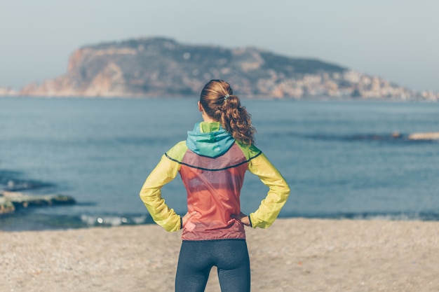 vrouw in fitness kleding permanent en kijken naar sein strand overdag