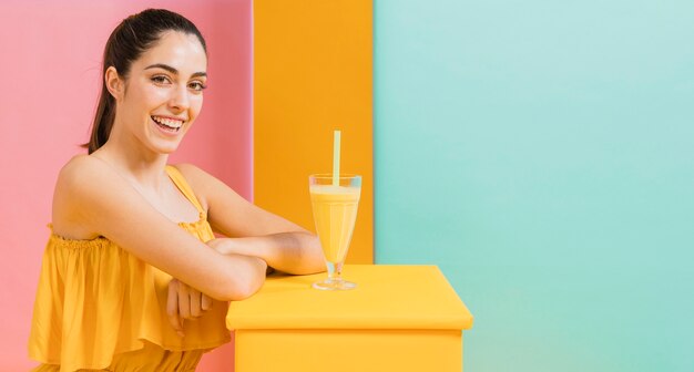 Vrouw in gele jurk met een glas sap