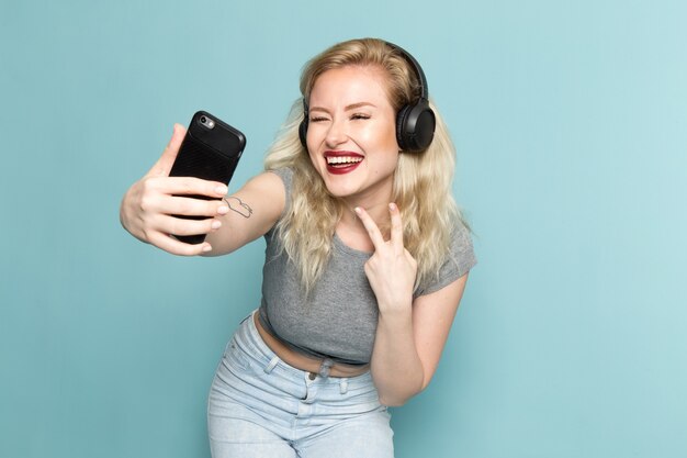 vrouw in grijs shirt en heldere blauwe spijkerbroek een selfie te nemen