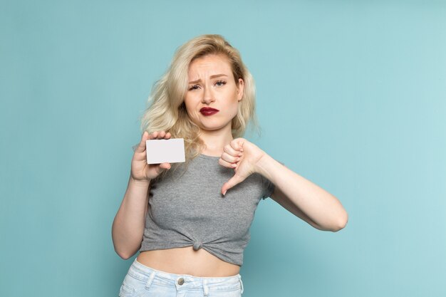 vrouw in grijs shirt en heldere blauwe spijkerbroek poseren met ontevreden uitdrukking