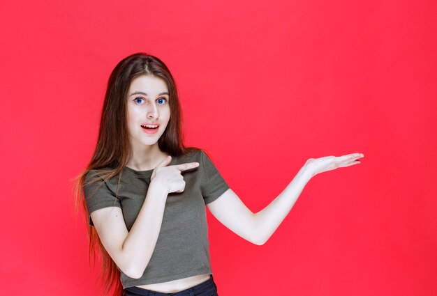 Vrouw in groen overhemd wijzend op iets in het oosten.