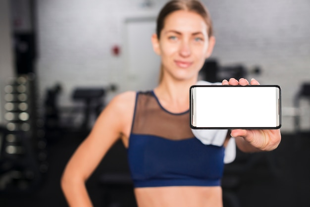 Gratis foto vrouw in gymnastiek met smartphonemalplaatje