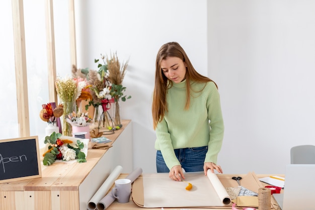 Gratis foto vrouw in haar bloemenwinkel met inpakpapier