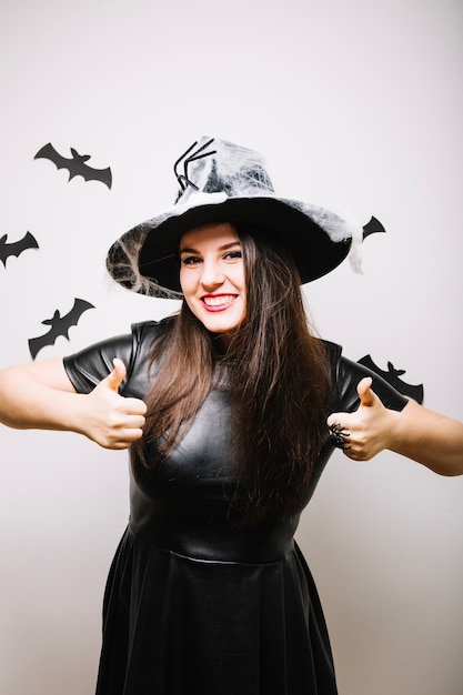 Vrouw in Halloween hoed met duimen omhoog