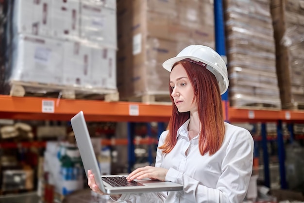 Vrouw in helm met opengeklapte laptop aan het werk