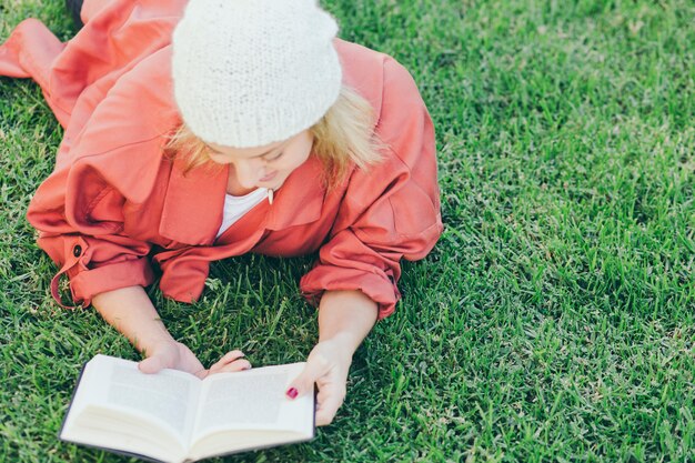 Vrouw in hoed lezen boek op gras