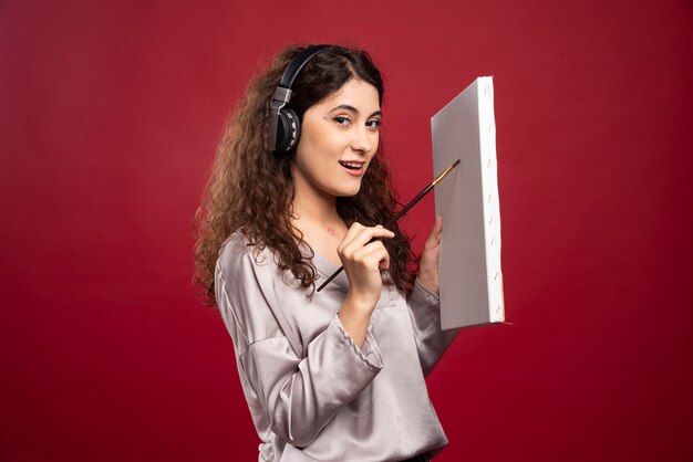 Vrouw in hoofdtelefoons die op canvas schilderen.