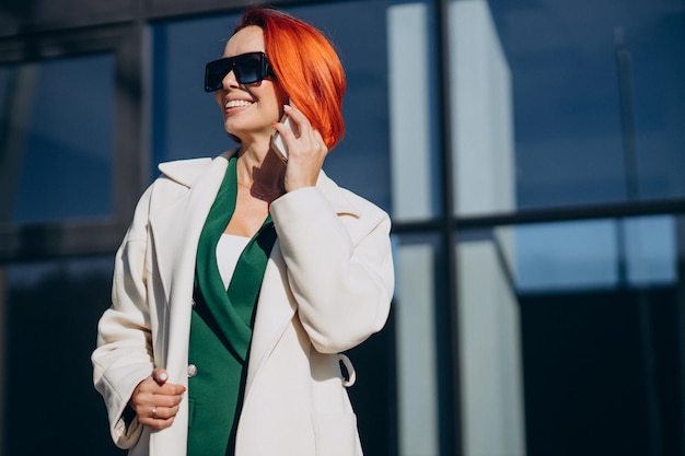 Vrouw in jas met telefoon buiten de straat