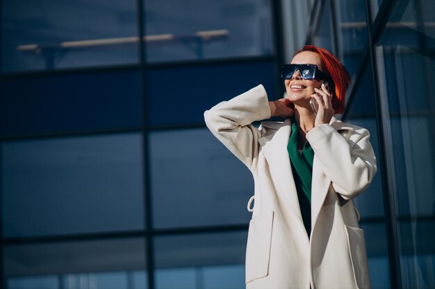 Vrouw in jas met telefoon buiten de straat