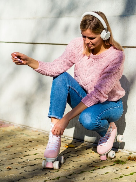 Vrouw in jeans met rolschaatsen en hoofdtelefoons