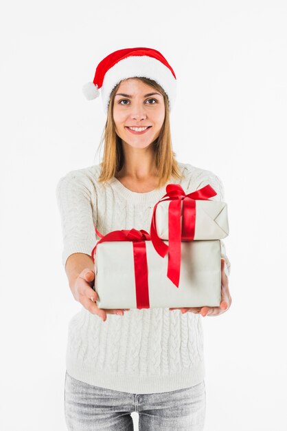 Vrouw in Kerstmanhoed die giftdozen met linten houden