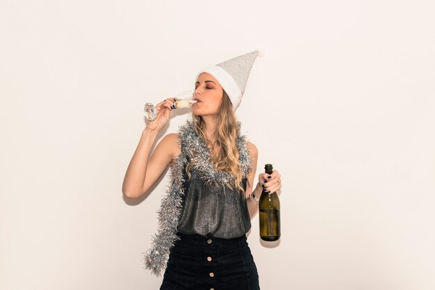 Vrouw in Kerstmanhoed het drinken champagne van glas