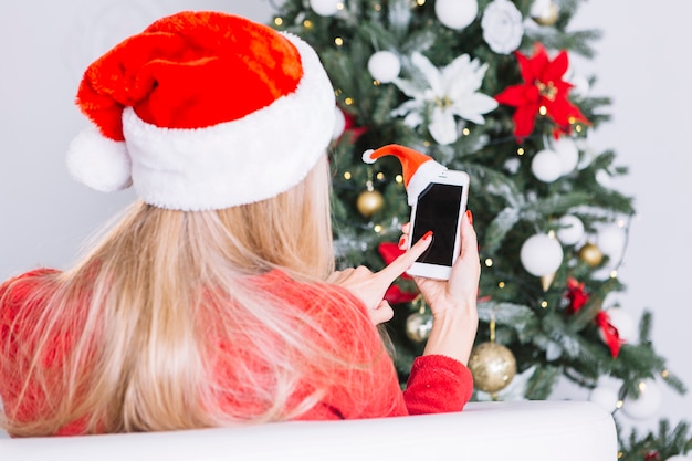 Vrouw in kerstmuts met telefoon in handen