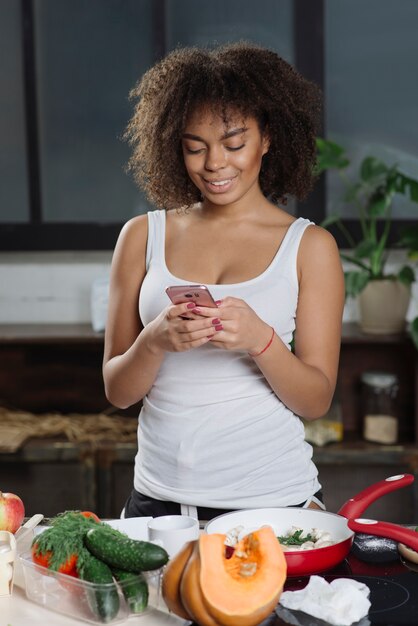 Vrouw in keuken het typen op smartphone