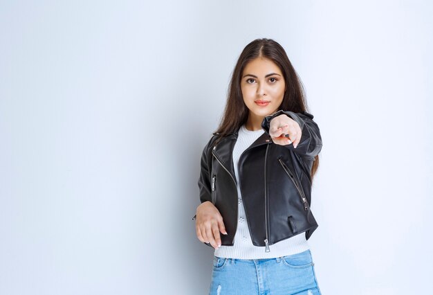 vrouw in leren jas wijzend op iemand vooruit.