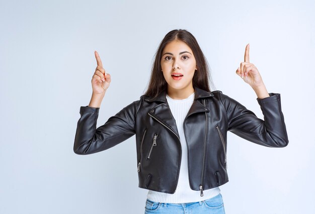 vrouw in leren jas wijzend op iets hierboven.