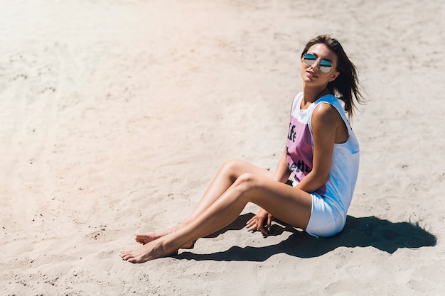 Vrouw in mouwloos onderhemd die op strand rusten