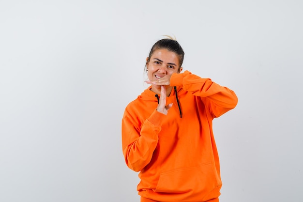 vrouw in oranje hoodie die een gebaar van een pauze toont en er vrolijk uitziet