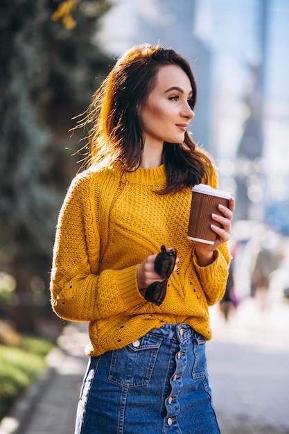 Vrouw in oranje trui koffie drinken