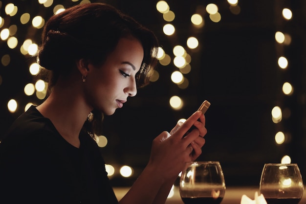 Vrouw in restaurant met behulp van de smartphone