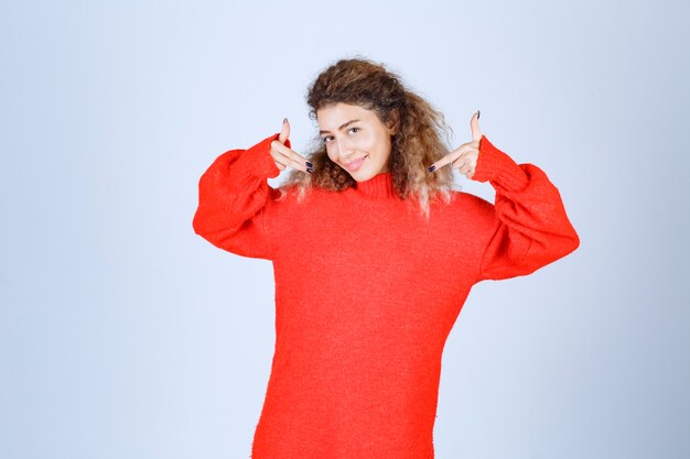 vrouw in rode sweatshirt wijzend op zichzelf.