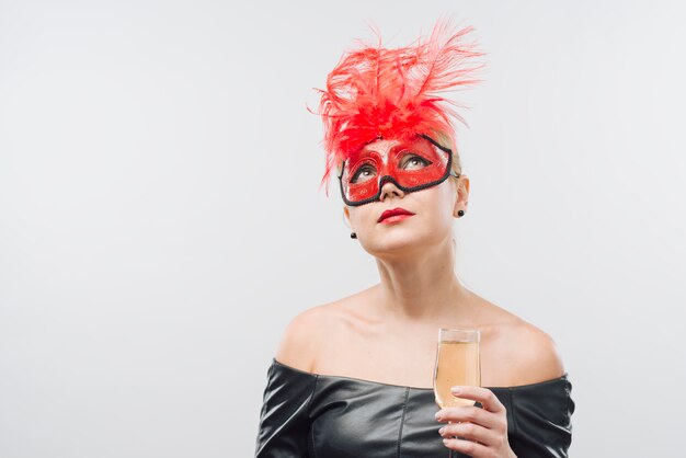 Vrouw in rood masker met champagneglas