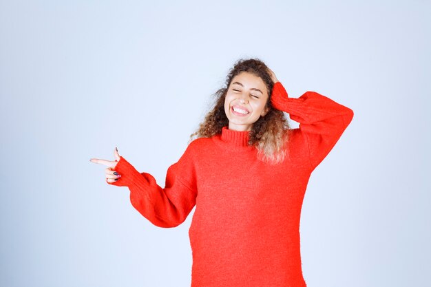 vrouw in rood overhemd wijzend op iets aan de linkerkant.