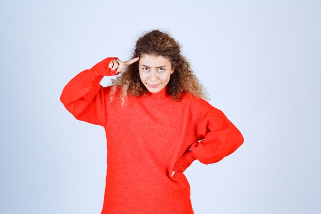 vrouw in rood shirt haar hoofd wijzend en denken.