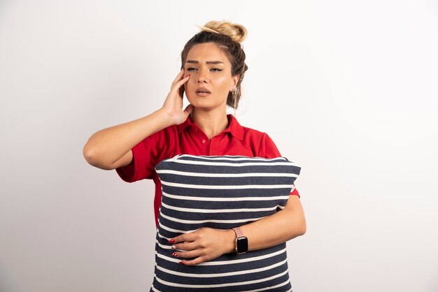 Vrouw in rood shirt knuffelen een kussen op witte achtergrond.