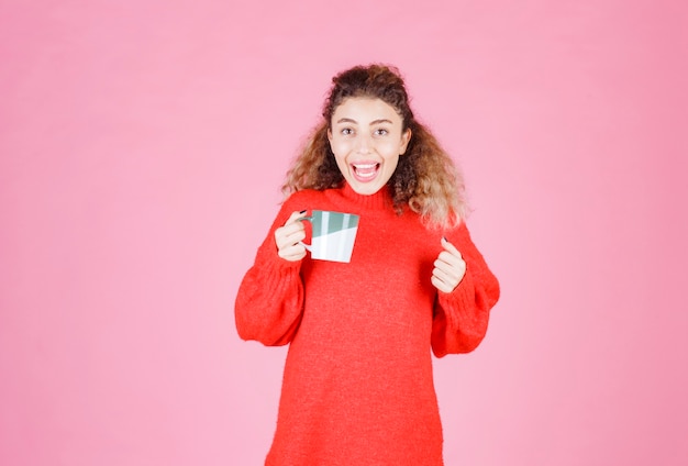 vrouw in rood shirt met een koffiemok en genietend van de smaak.