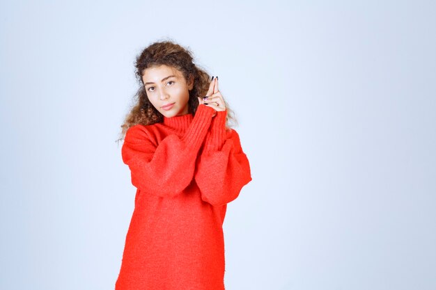 vrouw in rood sweatshirt dat pistoolteken toont.